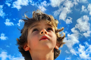 A child gazes up into the sky.